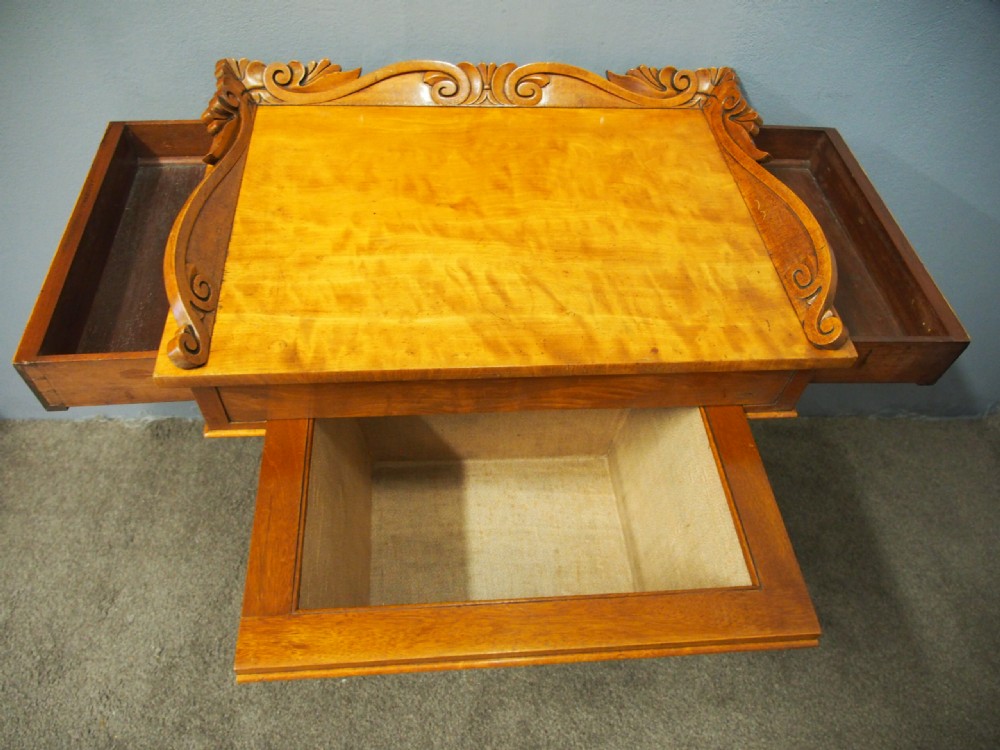 A Victorian satinwood work table featuring a carved top gallery, single drawer, pleated green silk work well, and carved trestle legs. View V