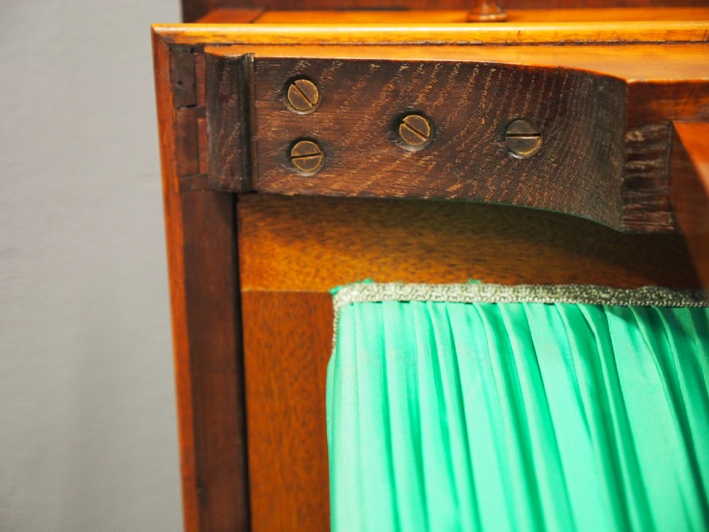 A Victorian satinwood work table featuring a carved top gallery, single drawer, pleated green silk work well, and carved trestle legs. View XII
