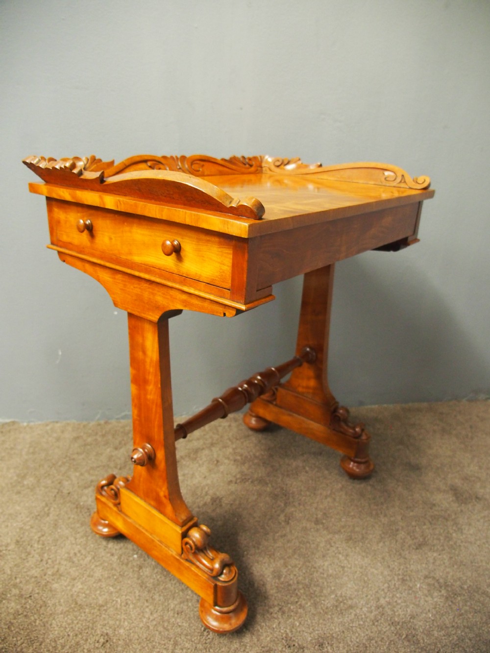 A Victorian satinwood work table featuring a carved top gallery, single drawer, pleated green silk work well, and carved trestle legs. View XIII