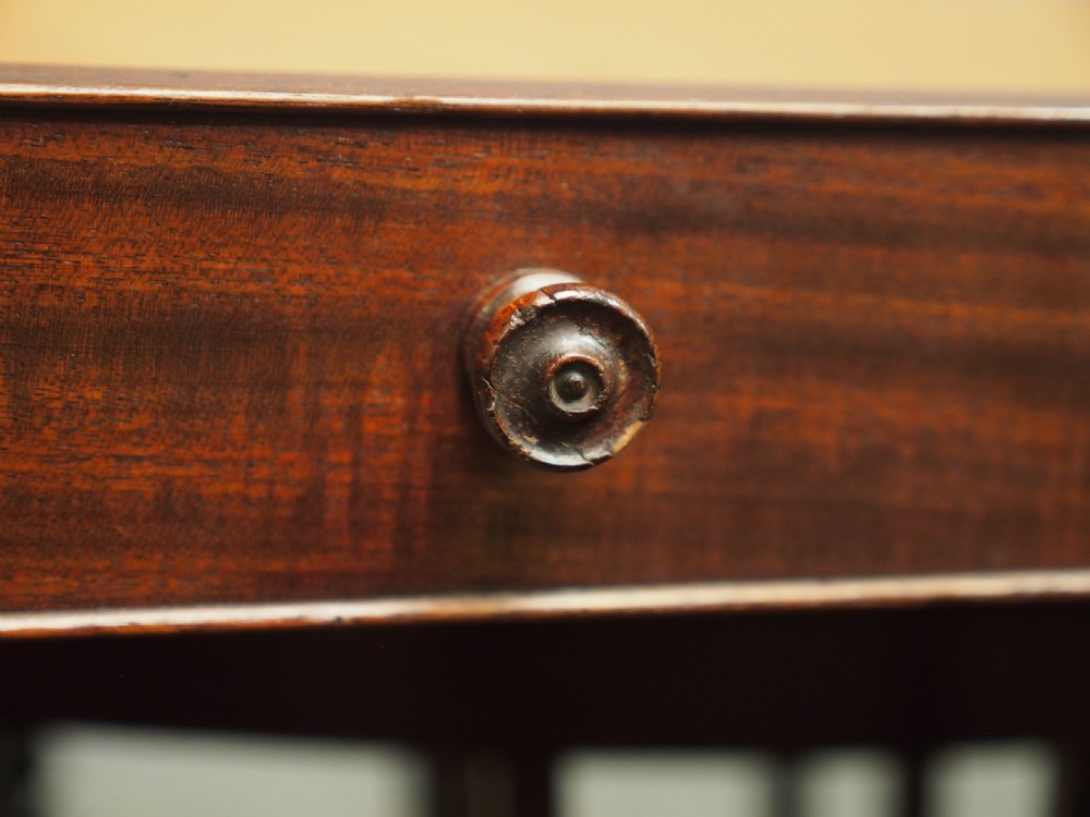 A George IV mahogany three-division Canterbury featuring turned corner posts with finials, slatted partitions, a single base drawer, and turned legs on brass castors. View II
