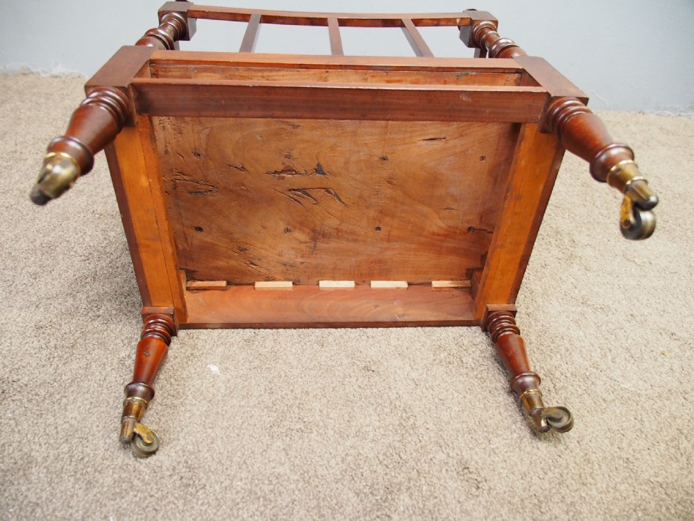A George IV mahogany three-division Canterbury featuring turned corner posts with finials, slatted partitions, a single base drawer, and turned legs on brass castors. View IV