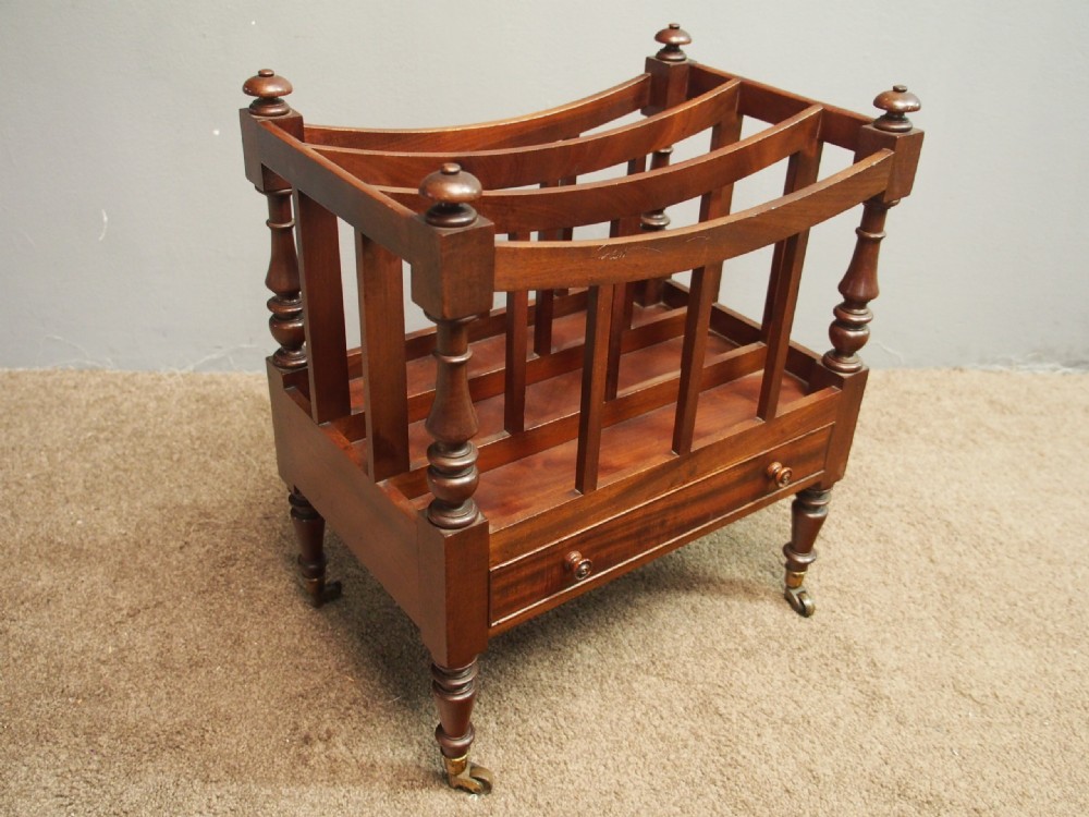 A George IV mahogany three-division Canterbury featuring turned corner posts with finials, slatted partitions, a single base drawer, and turned legs on brass castors. View V