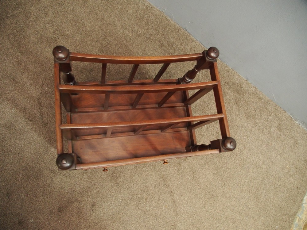 A George IV mahogany three-division Canterbury featuring turned corner posts with finials, slatted partitions, a single base drawer, and turned legs on brass castors. View IX