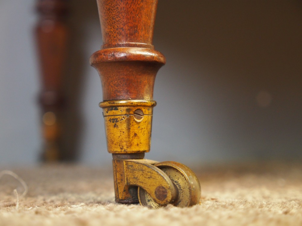 A George IV mahogany three-division Canterbury featuring turned corner posts with finials, slatted partitions, a single base drawer, and turned legs on brass castors. View XIII