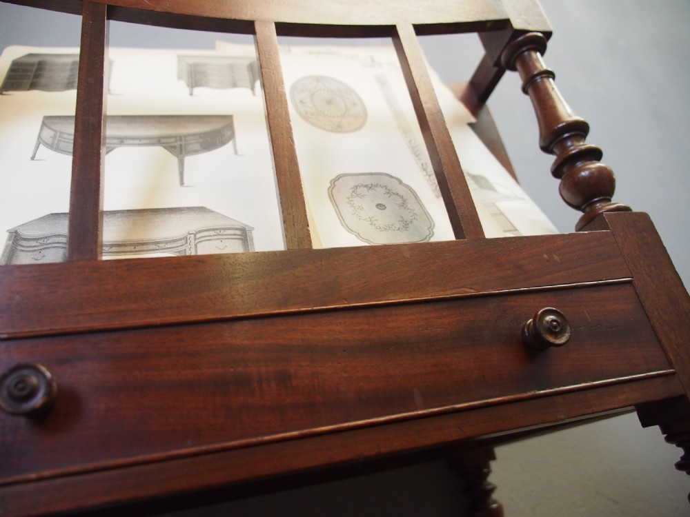 A George IV mahogany three-division Canterbury featuring turned corner posts with finials, slatted partitions, a single base drawer, and turned legs on brass castors. View XIV