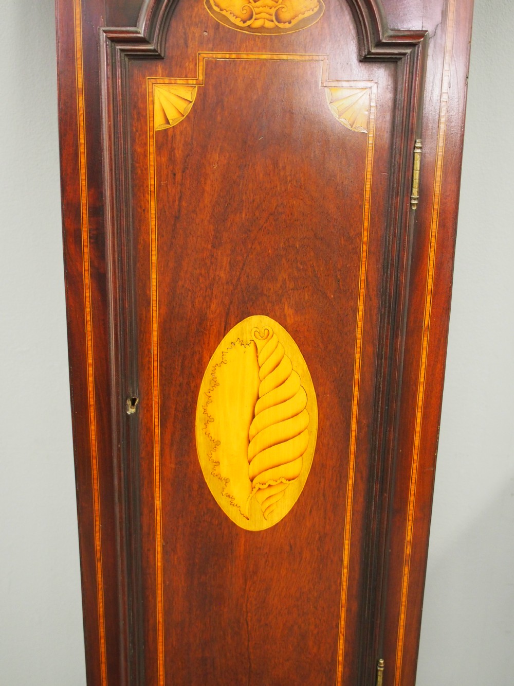 A tall Victorian mahogany longcase clock featuring a swan-neck pediment with fretwork, marquetry inlay, and a brass dial face. View II