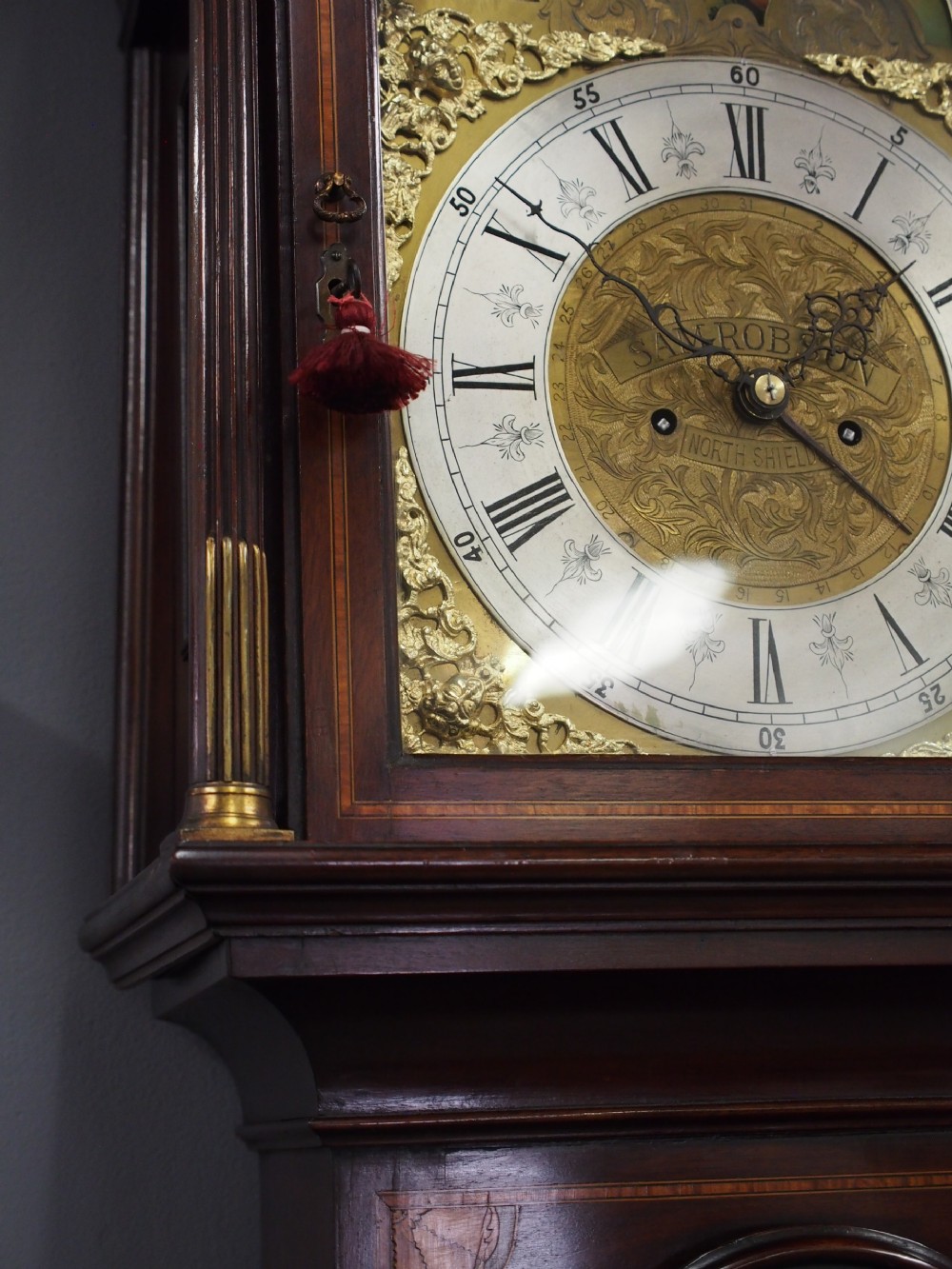 A tall Victorian mahogany longcase clock featuring a swan-neck pediment with fretwork, marquetry inlay, and a brass dial face. View IV