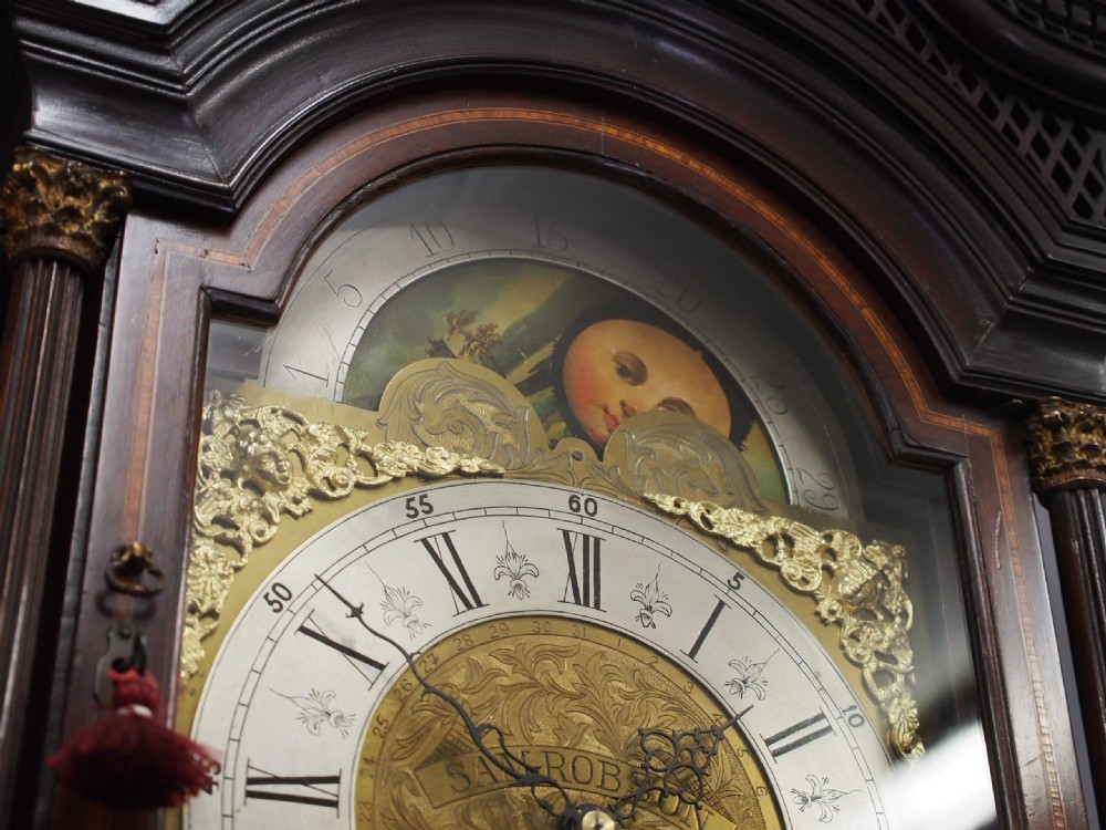 A tall Victorian mahogany longcase clock featuring a swan-neck pediment with fretwork, marquetry inlay, and a brass dial face. View VI