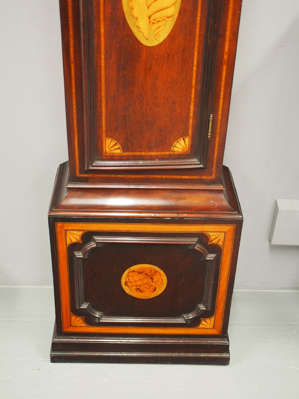 A tall Victorian mahogany longcase clock featuring a swan-neck pediment with fretwork, marquetry inlay, and a brass dial face. View IX