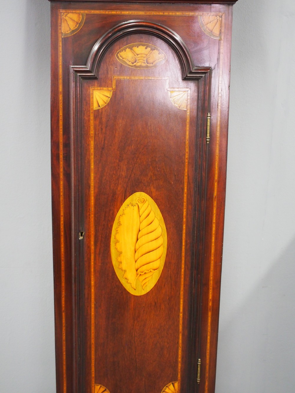 A tall Victorian mahogany longcase clock featuring a swan-neck pediment with fretwork, marquetry inlay, and a brass dial face. View X