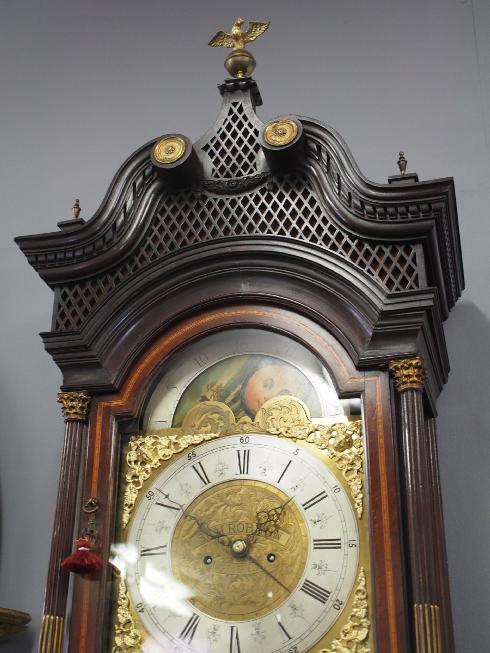 A tall Victorian mahogany longcase clock featuring a swan-neck pediment with fretwork, marquetry inlay, and a brass dial face. View XI