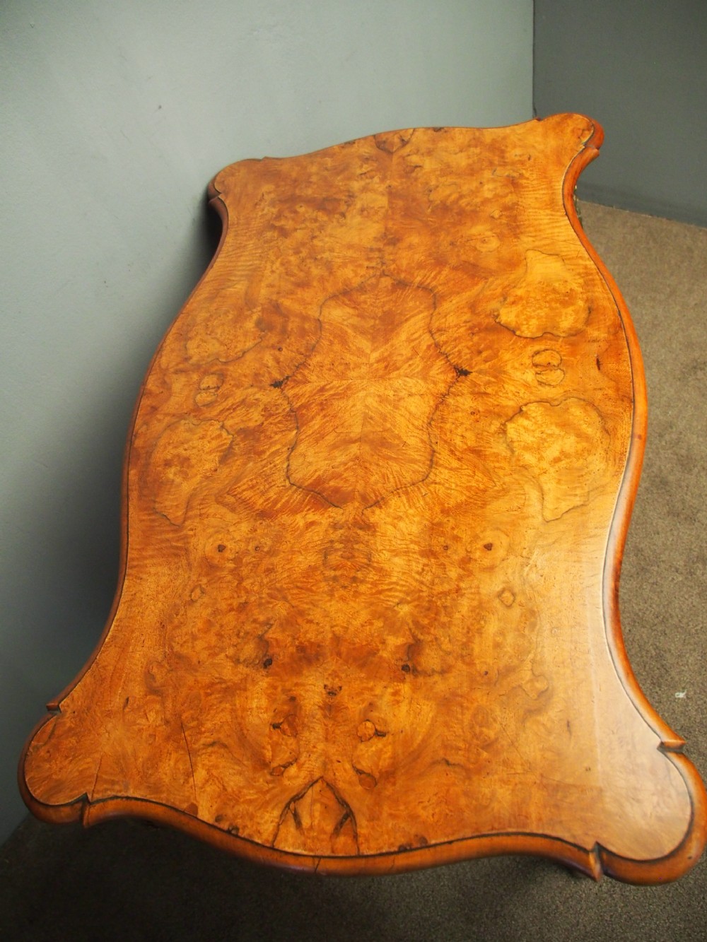 A Louis XV style burr walnut bureau plat featuring a serpentine top, cabriole legs, and ornate gilt-bronze mounts. View III