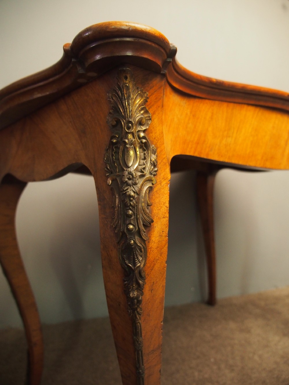 A Louis XV style burr walnut bureau plat featuring a serpentine top, cabriole legs, and ornate gilt-bronze mounts. View V