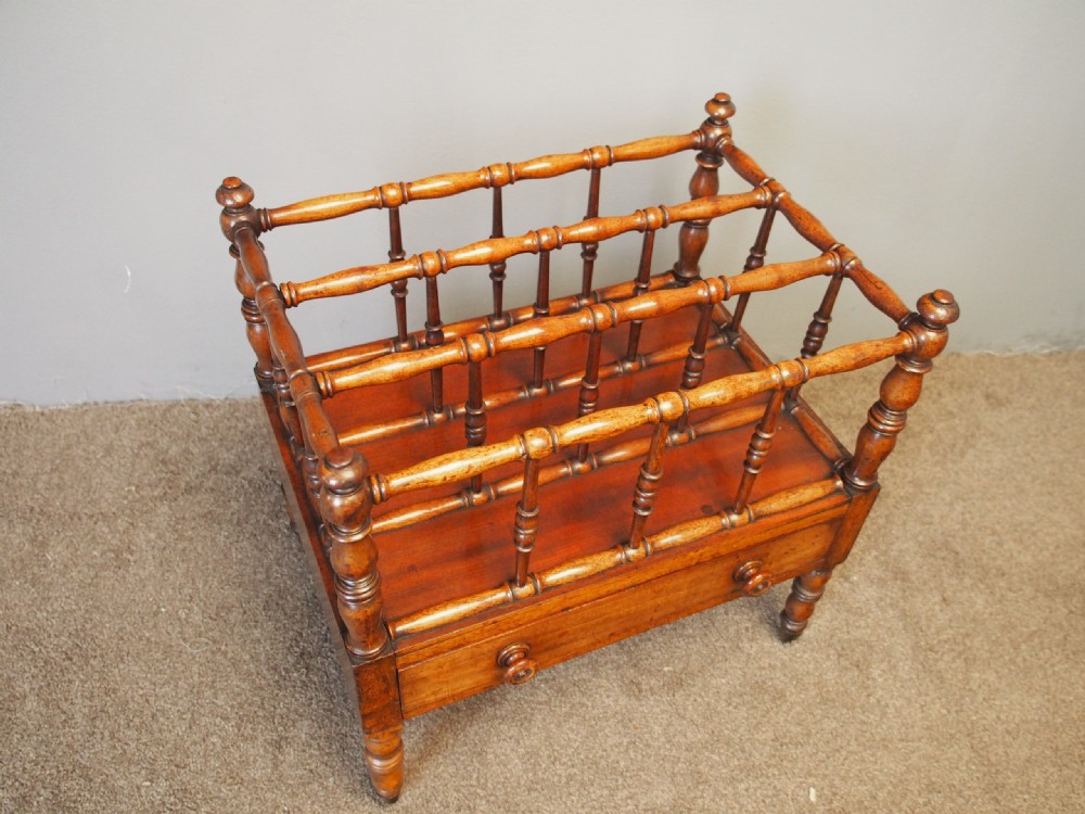 A George IV mahogany Canterbury featuring four slatted compartments with turned spindles, a single base drawer with turned wooden knobs, and turned legs ending in brass castors. View III