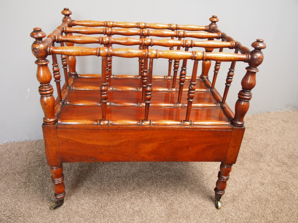 A George IV mahogany Canterbury featuring four slatted compartments with turned spindles, a single base drawer with turned wooden knobs, and turned legs ending in brass castors. View VI