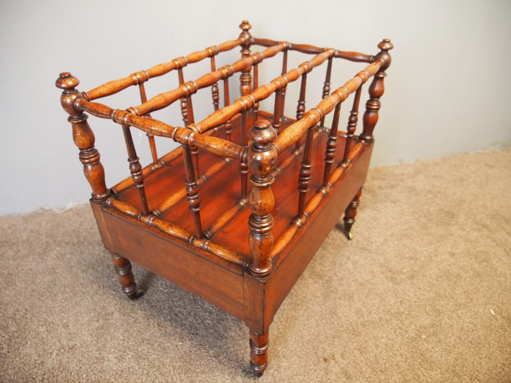 A George IV mahogany Canterbury featuring four slatted compartments with turned spindles, a single base drawer with turned wooden knobs, and turned legs ending in brass castors. View VII