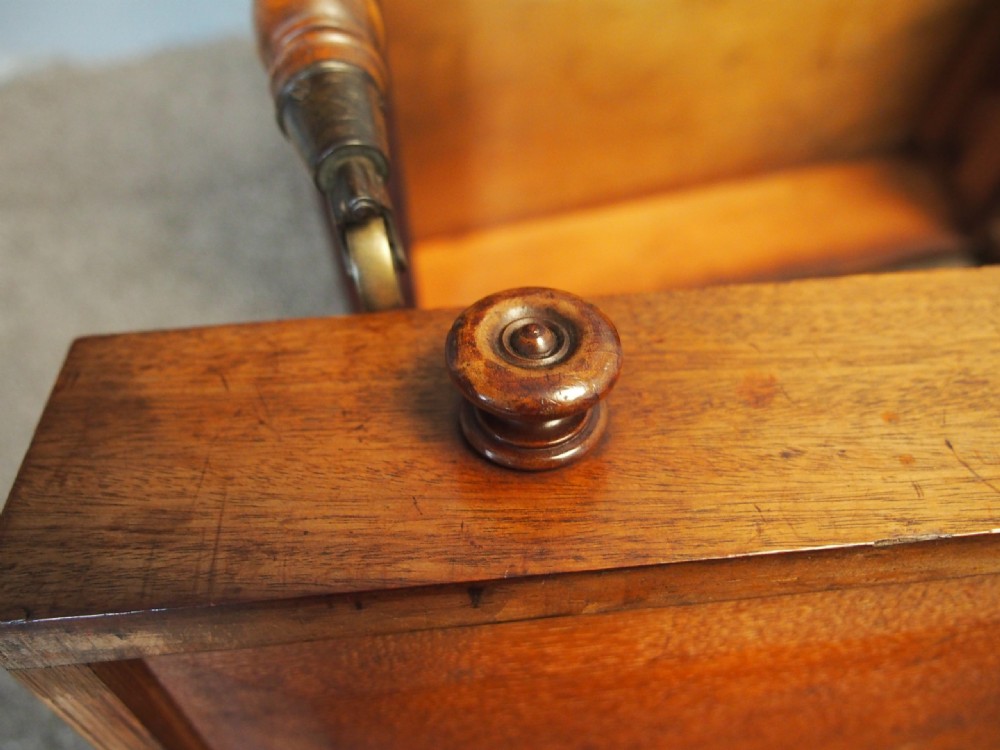 A George IV mahogany Canterbury featuring four slatted compartments with turned spindles, a single base drawer with turned wooden knobs, and turned legs ending in brass castors. View IX
