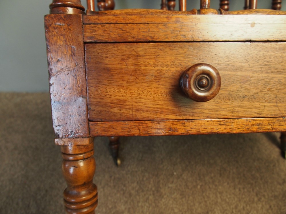 A George IV mahogany Canterbury featuring four slatted compartments with turned spindles, a single base drawer with turned wooden knobs, and turned legs ending in brass castors. View XIII