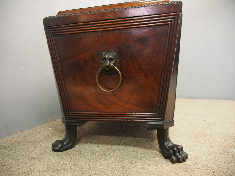 A Scottish Regency mahogany sarcophagus-shaped wine cooler featuring carved claw feet, gadrooned moulding, and side brass lion-mask drop ring handles. View V