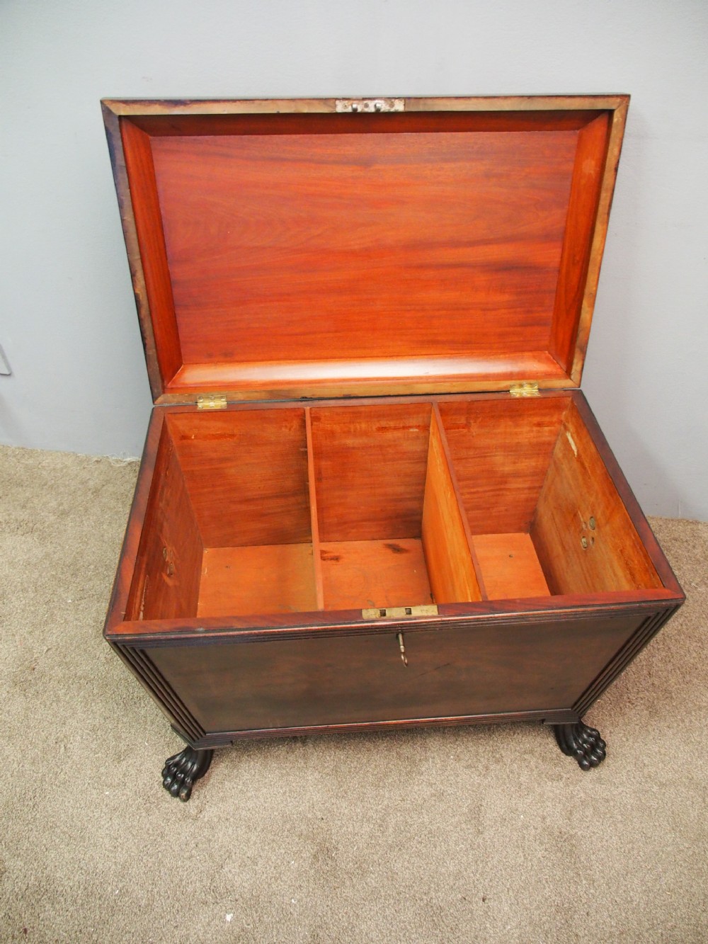 A Scottish Regency mahogany sarcophagus-shaped wine cooler featuring carved claw feet, gadrooned moulding, and side brass lion-mask drop ring handles. View VI