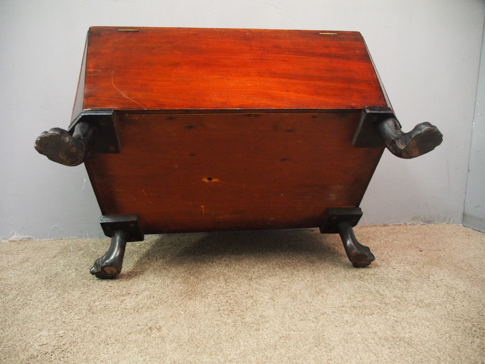 A Scottish Regency mahogany sarcophagus-shaped wine cooler featuring carved claw feet, gadrooned moulding, and side brass lion-mask drop ring handles. View X