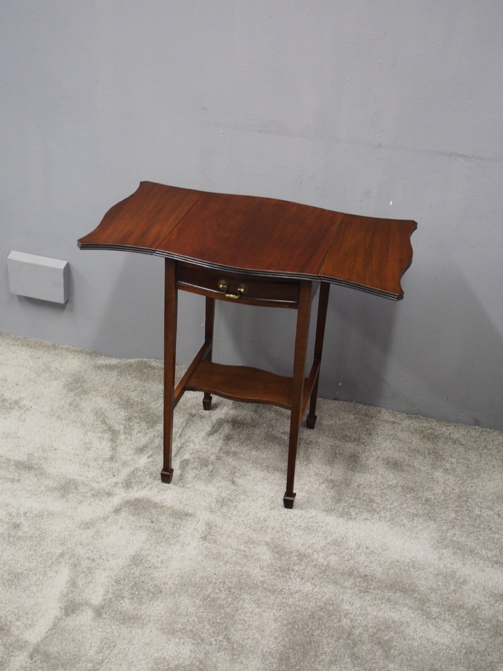 A Georgian style dark mahogany Pembroke table featuring two hinged drop leaves, a single frieze drawer with a brass pull handle, a lower undertier, and four straight legs. View IV