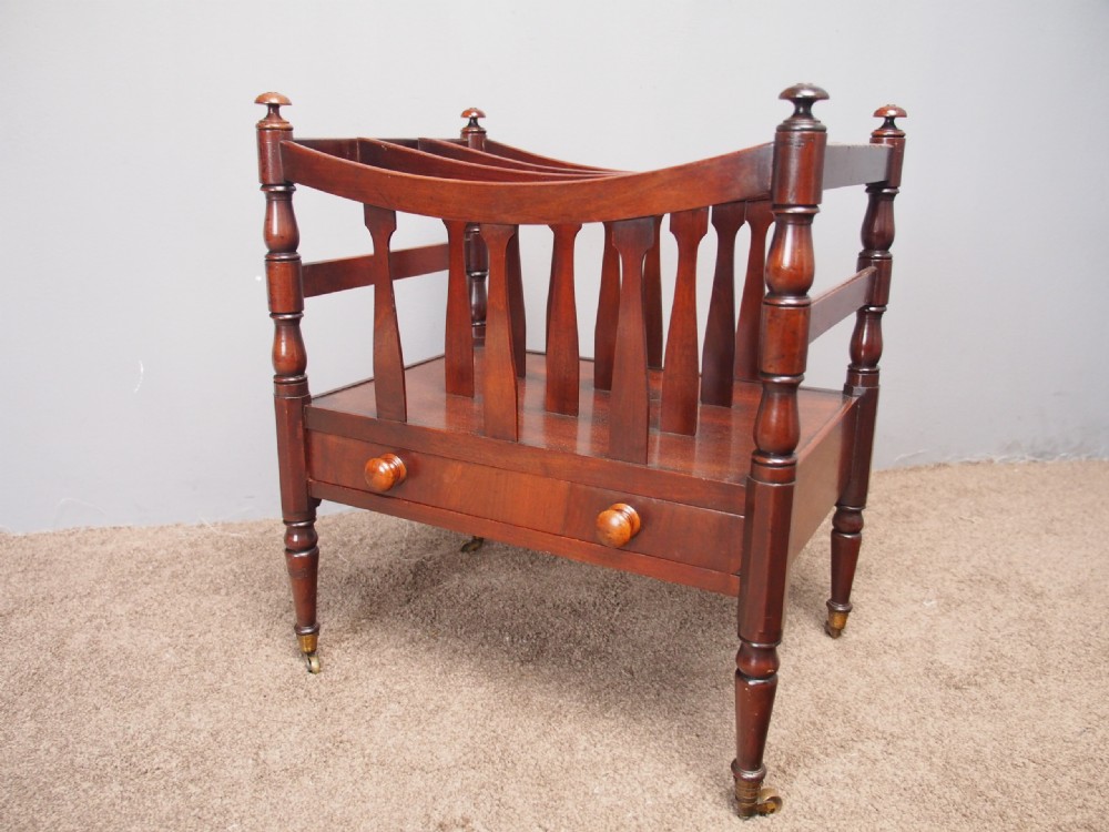 A George IV mahogany bowed canterbury featuring four open compartments, turned corner posts with finials, a lower drawer, and turned legs on brass castors. View II