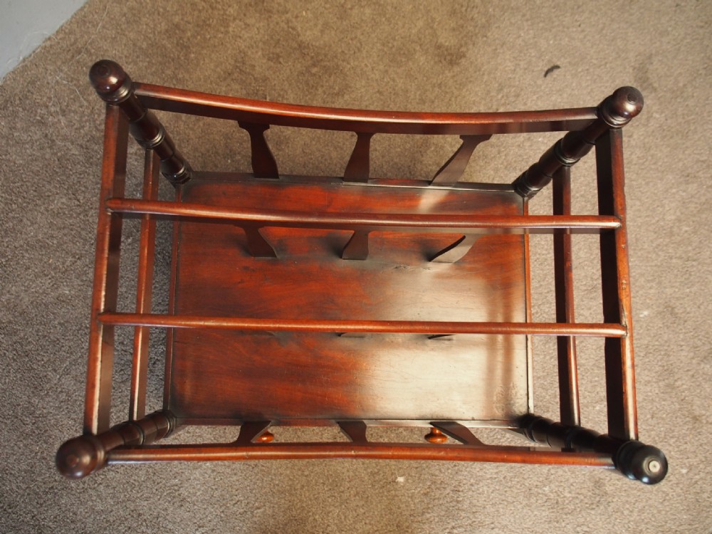 A George IV mahogany bowed canterbury featuring four open compartments, turned corner posts with finials, a lower drawer, and turned legs on brass castors. View III