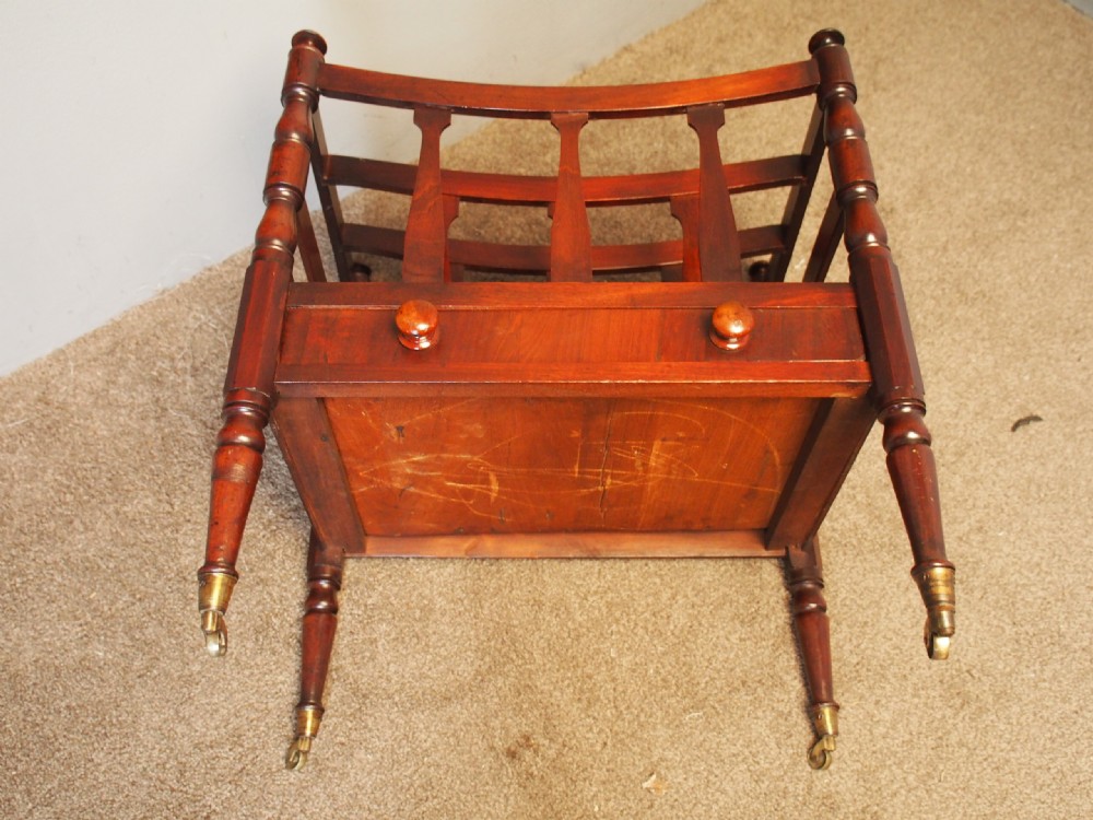 A George IV mahogany bowed canterbury featuring four open compartments, turned corner posts with finials, a lower drawer, and turned legs on brass castors. View IV