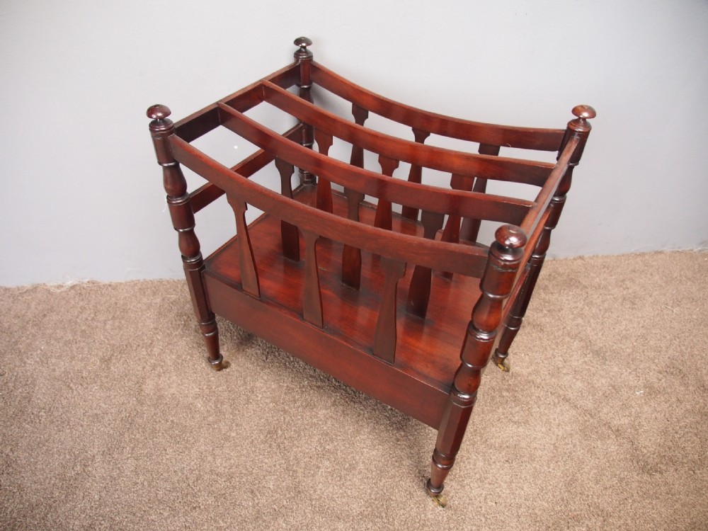 A George IV mahogany bowed canterbury featuring four open compartments, turned corner posts with finials, a lower drawer, and turned legs on brass castors. View V