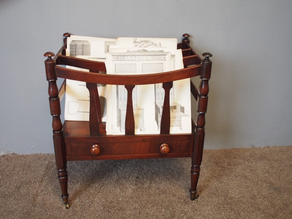 A George IV mahogany bowed canterbury featuring four open compartments, turned corner posts with finials, a lower drawer, and turned legs on brass castors. View VI