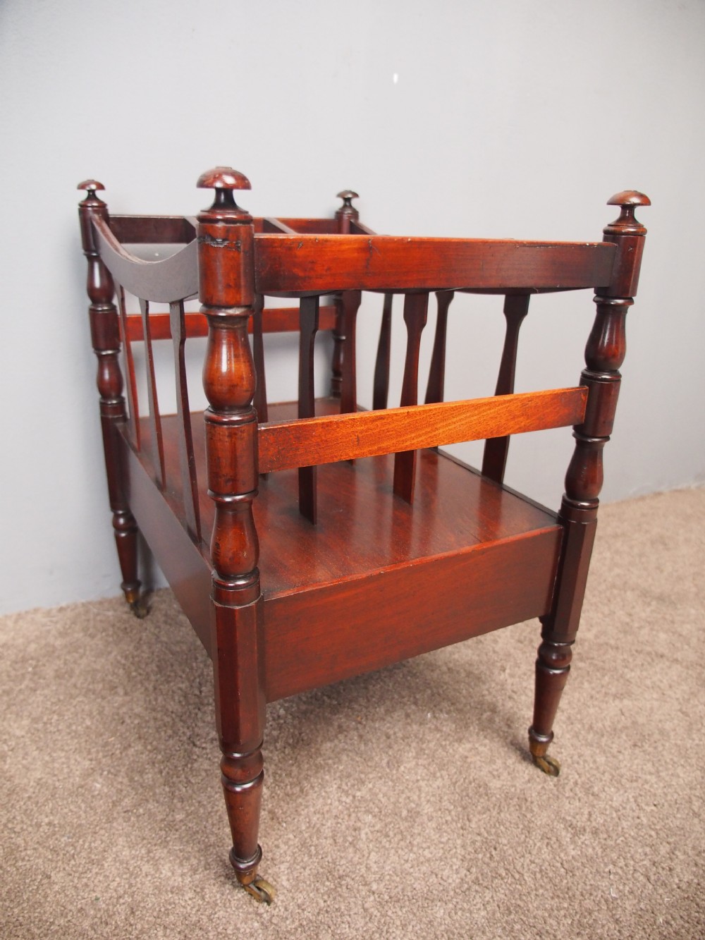 A George IV mahogany bowed canterbury featuring four open compartments, turned corner posts with finials, a lower drawer, and turned legs on brass castors. View VII