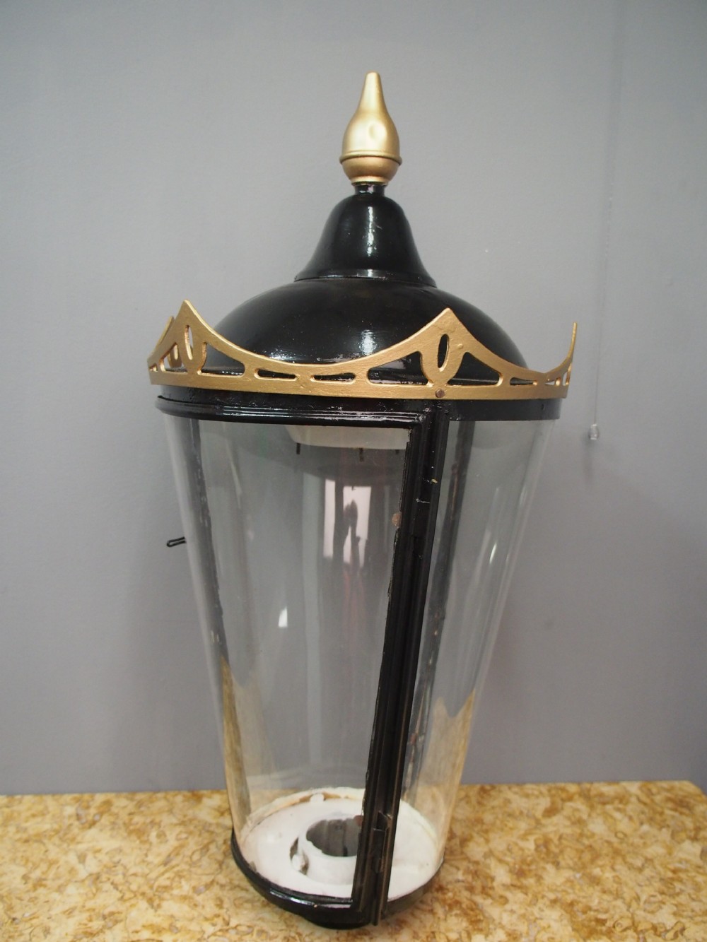 A tapered circular street lamp lantern featuring a black domed cap with a gold finial, gold filigree trim, and clear glass side panels. View II