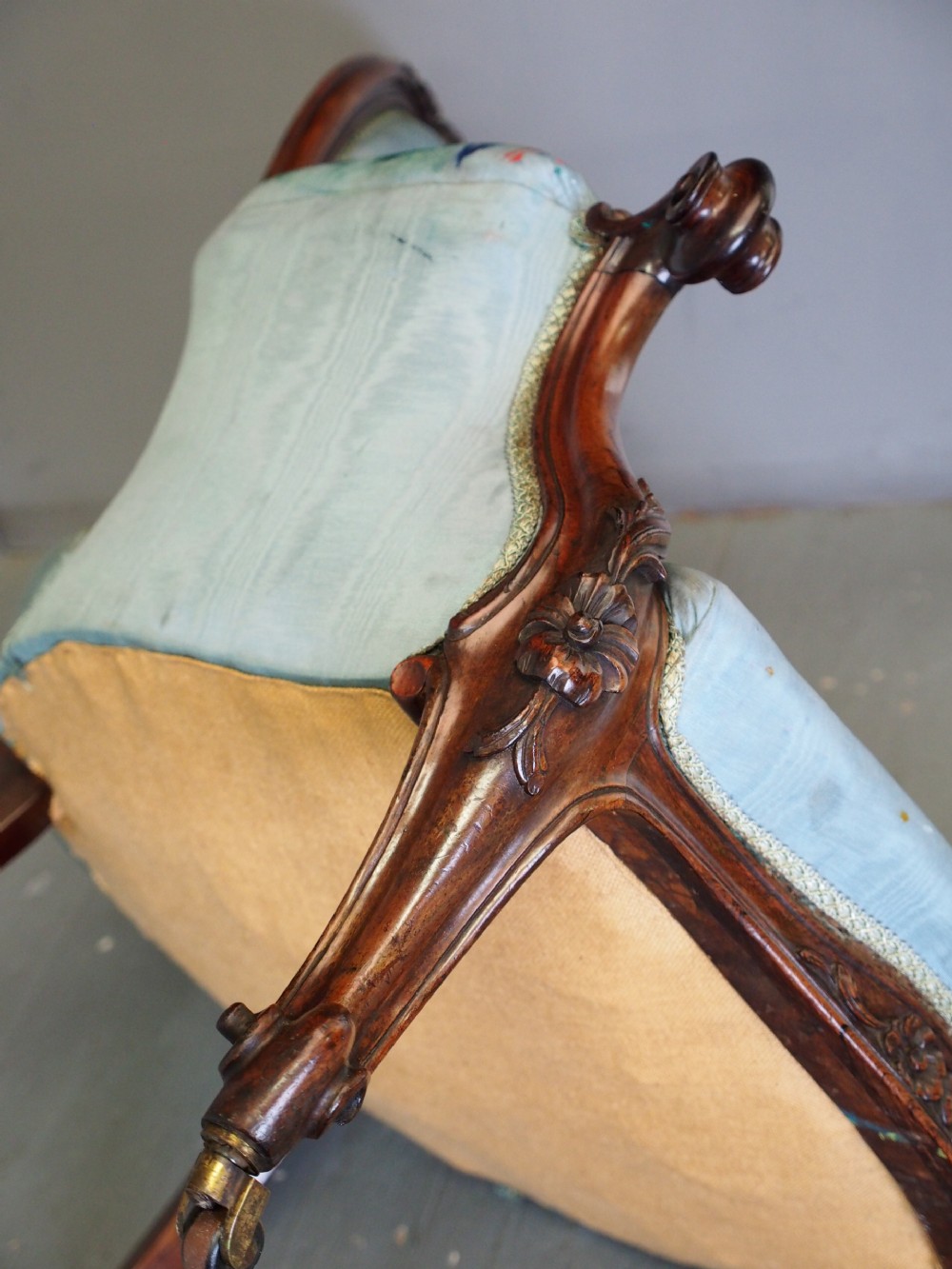 A Victorian carved walnut armchair featuring light blue button-tufted backrest upholstery, padded armrests, cabriole front legs, and metal castors. View VII