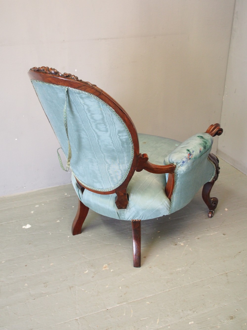 A Victorian carved walnut armchair featuring light blue button-tufted backrest upholstery, padded armrests, cabriole front legs, and metal castors. View VIII