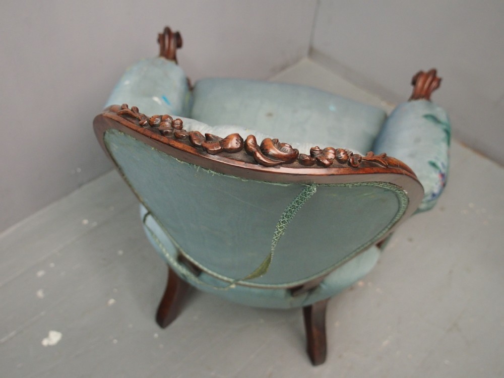 A Victorian carved walnut armchair featuring light blue button-tufted backrest upholstery, padded armrests, cabriole front legs, and metal castors. View IX