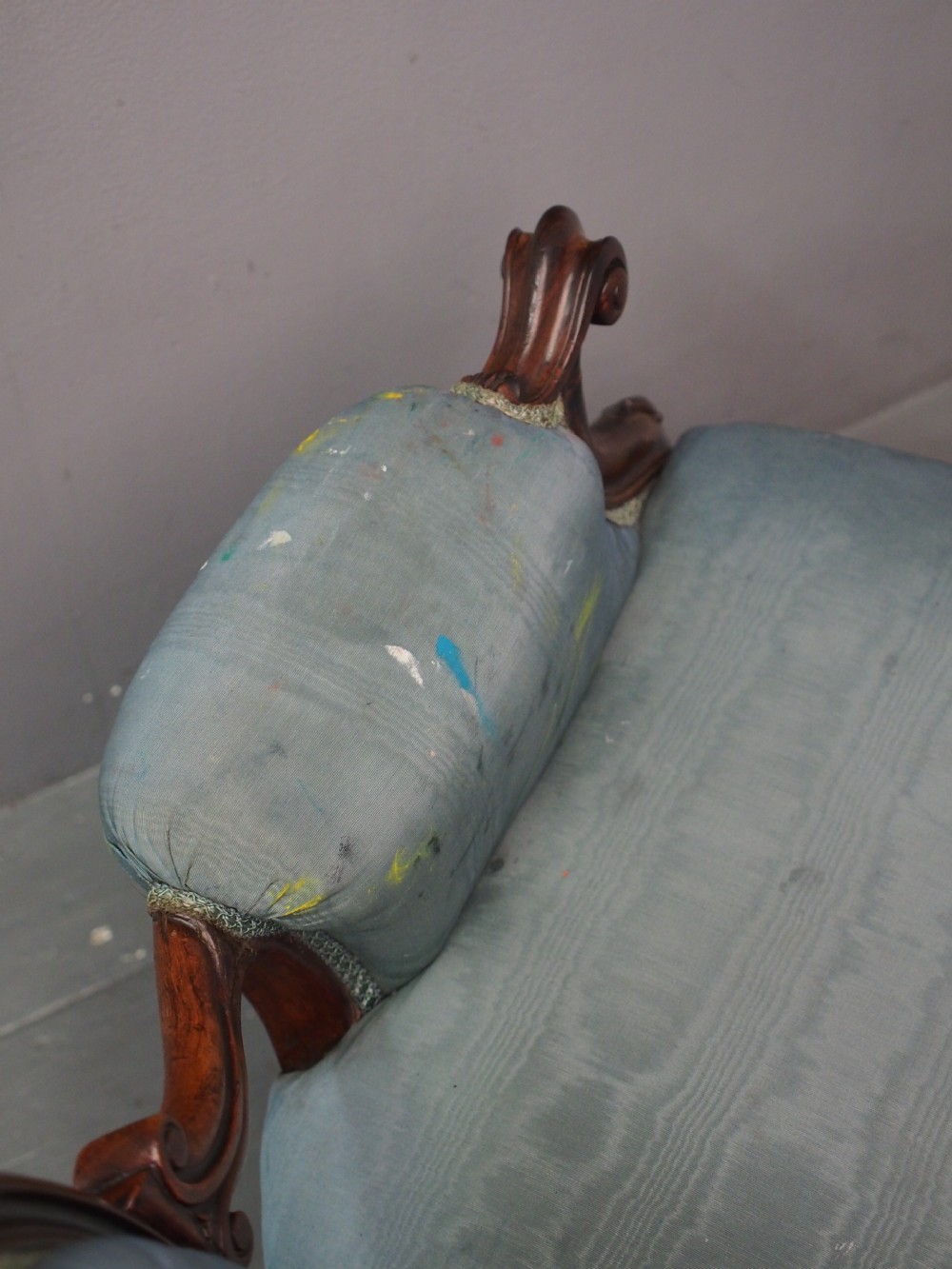 A Victorian carved walnut armchair featuring light blue button-tufted backrest upholstery, padded armrests, cabriole front legs, and metal castors. View X