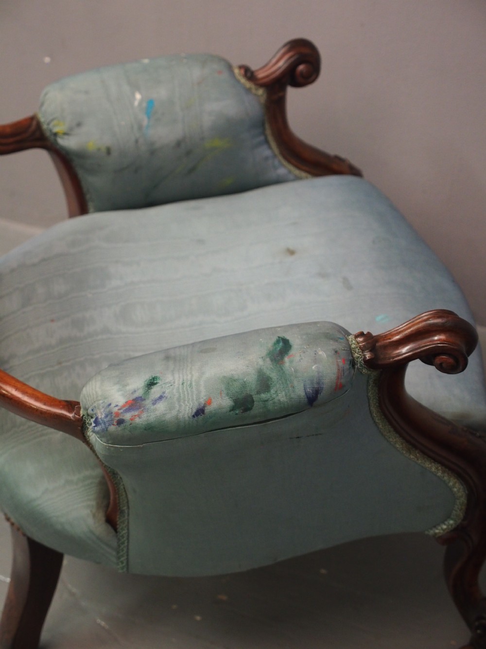 A Victorian carved walnut armchair featuring light blue button-tufted backrest upholstery, padded armrests, cabriole front legs, and metal castors. View XII