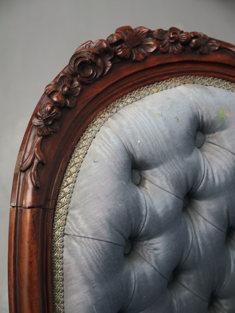 A Victorian carved walnut armchair featuring light blue button-tufted backrest upholstery, padded armrests, cabriole front legs, and metal castors. View XIII