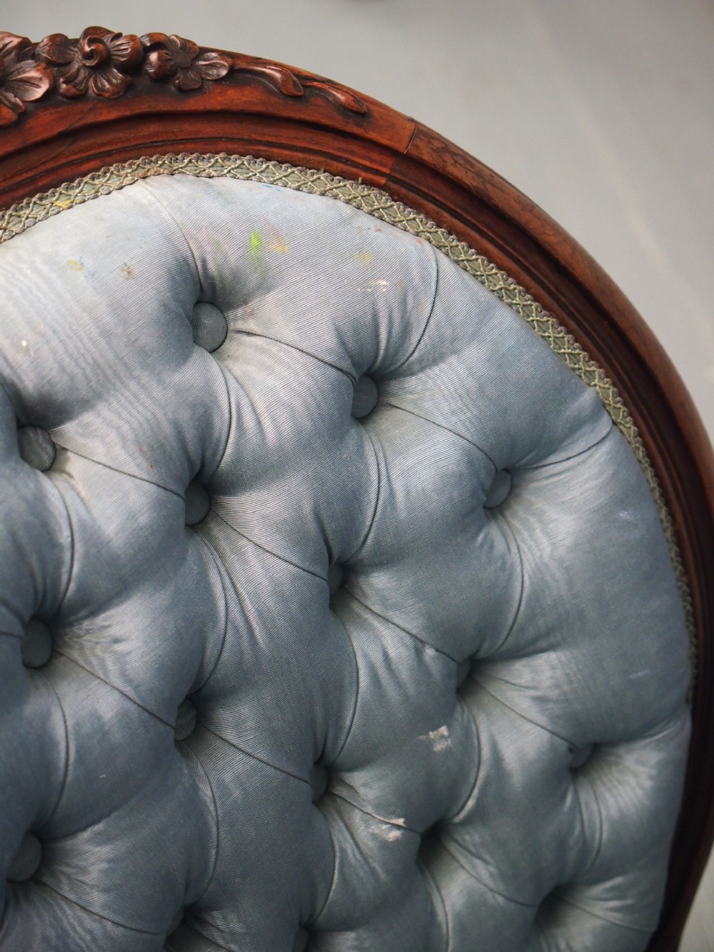 A Victorian carved walnut armchair featuring light blue button-tufted backrest upholstery, padded armrests, cabriole front legs, and metal castors. View XIV