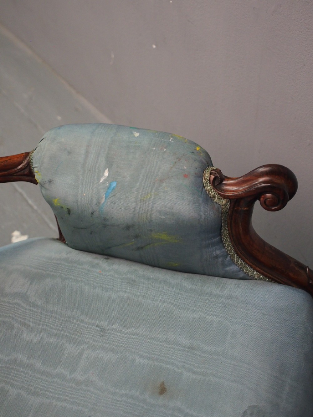 A Victorian carved walnut armchair featuring light blue button-tufted backrest upholstery, padded armrests, cabriole front legs, and metal castors. View XV