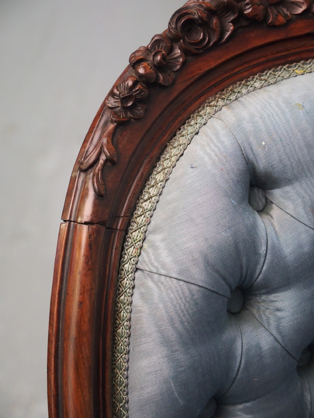 A Victorian carved walnut armchair featuring light blue button-tufted backrest upholstery, padded armrests, cabriole front legs, and metal castors. View XVI