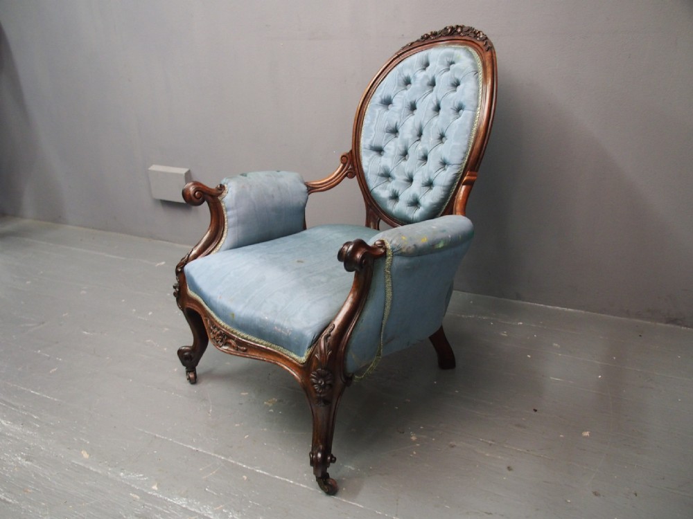 A Victorian carved walnut armchair featuring light blue button-tufted backrest upholstery, padded armrests, cabriole front legs, and metal castors. View XVII