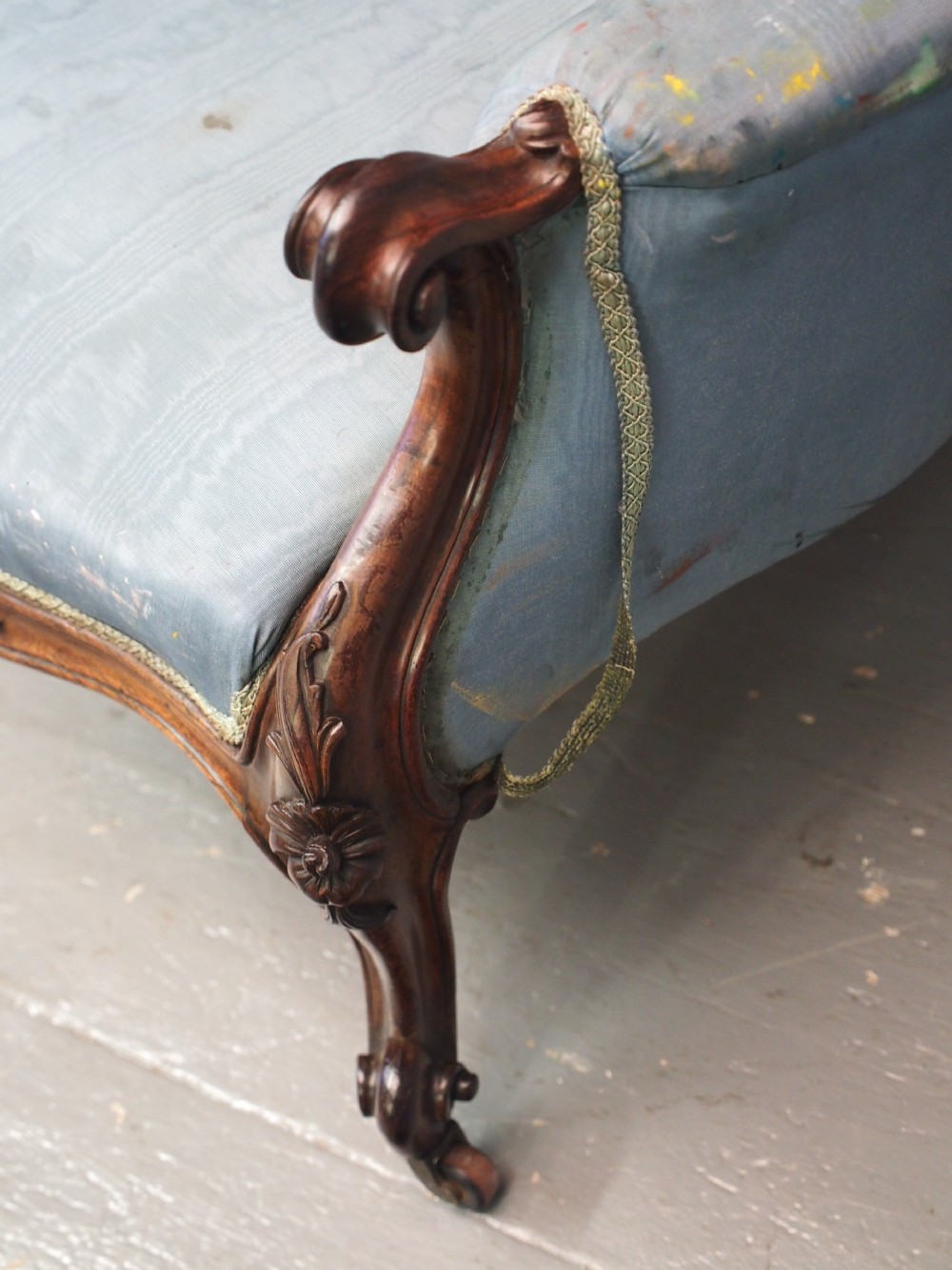 A Victorian carved walnut armchair featuring light blue button-tufted backrest upholstery, padded armrests, cabriole front legs, and metal castors. View XX