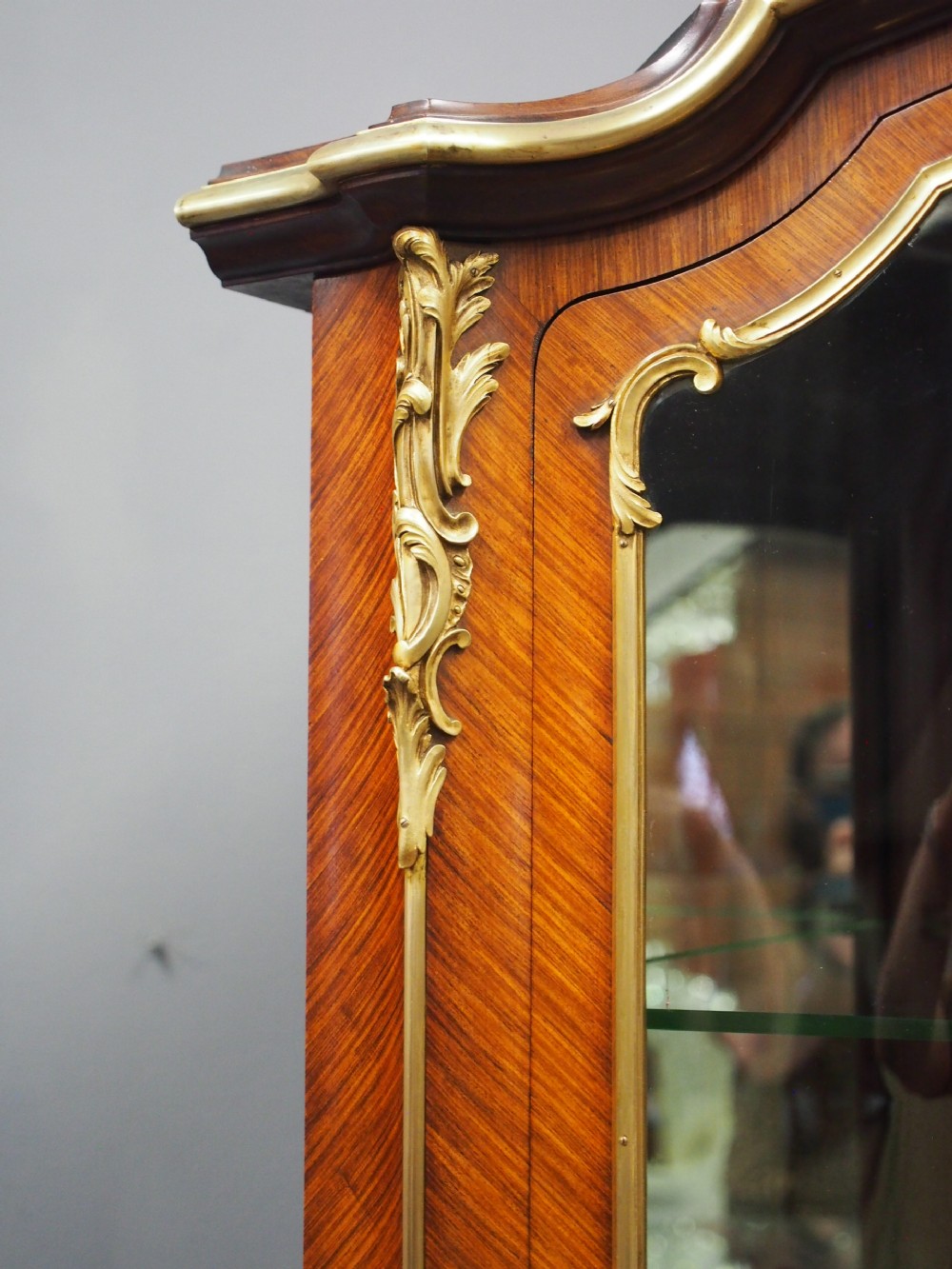 A Victorian corner vitrine in kingwood featuring curved glass doors, floral marquetry on the lower panel, and ornate brass ormolu mounts. View V