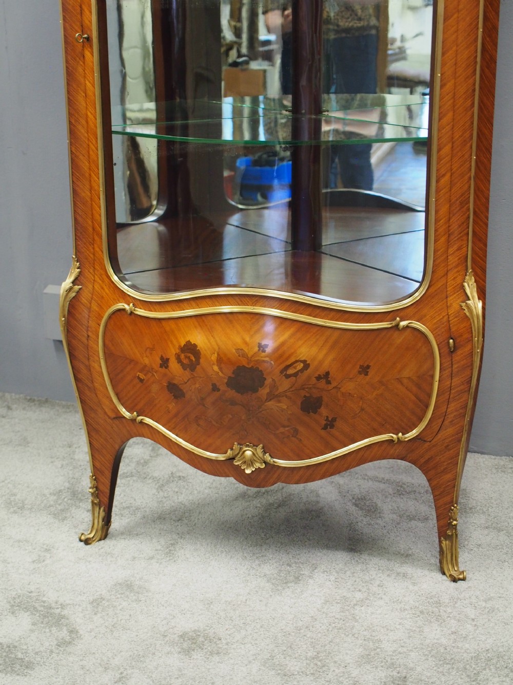 A Victorian corner vitrine in kingwood featuring curved glass doors, floral marquetry on the lower panel, and ornate brass ormolu mounts. View XI