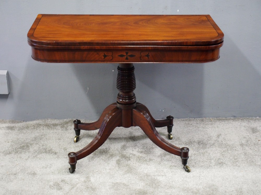 A Regency mahogany foldover card table featuring rosewood inlay along the apron, a turned central pedestal, and four swept legs with brass castors. View IV