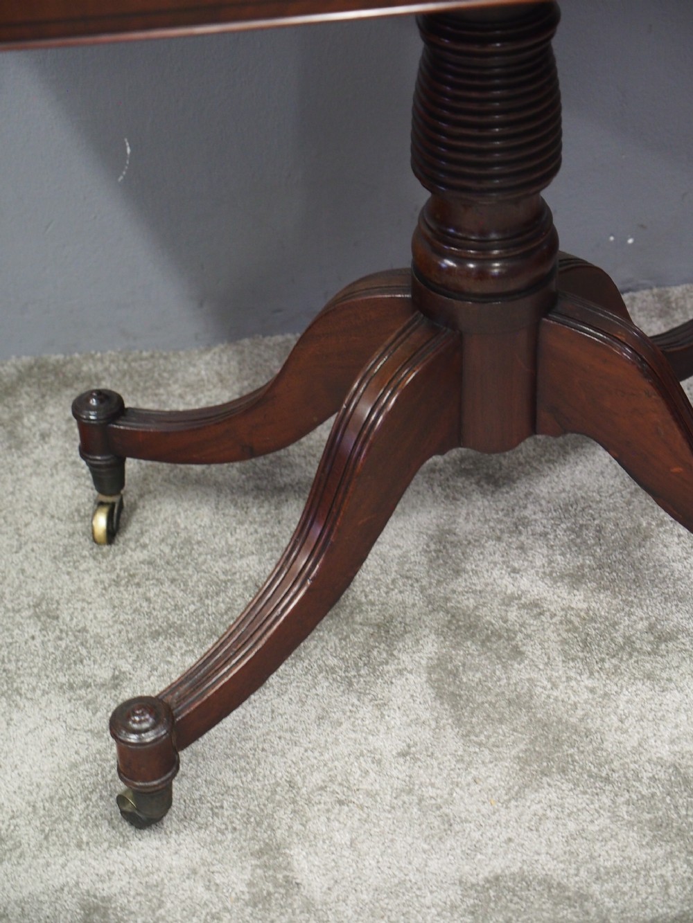 A Regency mahogany foldover card table featuring rosewood inlay along the apron, a turned central pedestal, and four swept legs with brass castors. View V