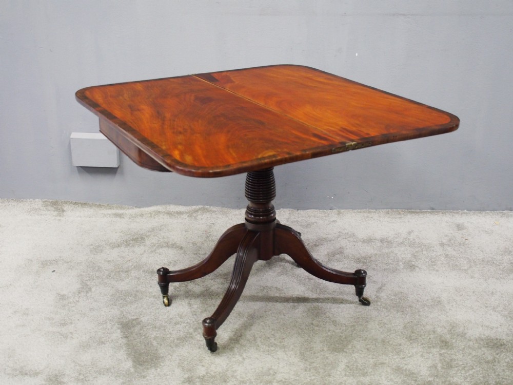 A Regency mahogany foldover card table featuring rosewood inlay along the apron, a turned central pedestal, and four swept legs with brass castors. View VII