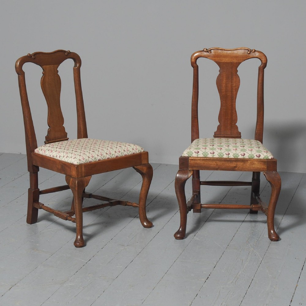 A pair of small Queen Anne style mahogany childrens chairs featuring vase-shaped back splats, cabriole front legs, and patterned upholstered seats.